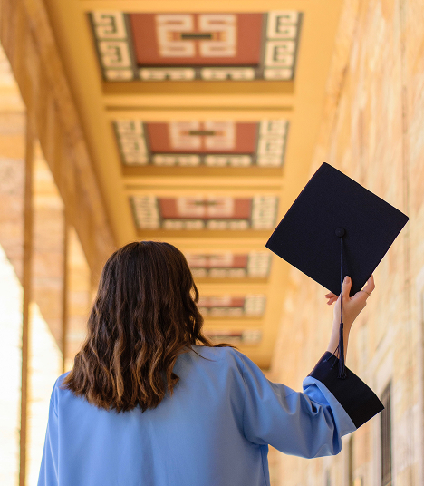 A graduate holding up her cap